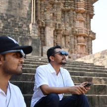 two men sitting on some stairs looking at a cell phone