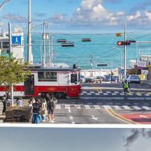 a red and white bus driving down a street next to the ocean