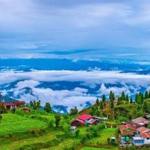 a group of houses on a green hill with clouds