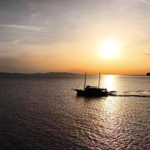 una barca in acqua con il tramonto sullo sfondo
