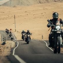 a group of people riding motorcycles down a road