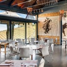 a restaurant with tables and white chairs and windows