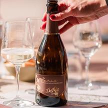 henkilö avaa viinipullon pöydällä laseineen