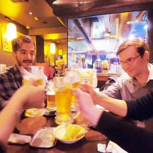 a group of people sitting around a table drinking beer