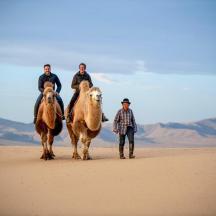 a group of people riding horses in the desert