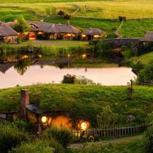 a house in the middle of a field with a pond