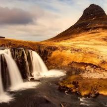 a waterfall in front of a mountain