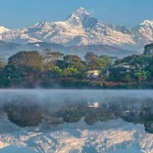 a misty lake with a mountain range in the background