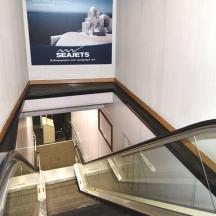 un escalator dans un immeuble avec un panneau sur le mur