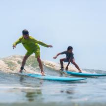 two men riding a wave on surfboards in the ocean
