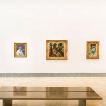 a coffee table in front of a wall with paintings