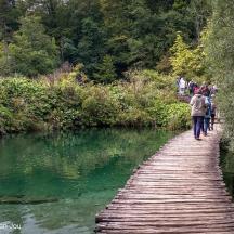 orang berjalan di atas jambatan kayu di atas sungai