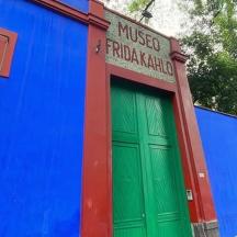 um prédio colorido com uma porta verde e uma árvore