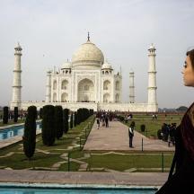 a woman standing in front of the taj mahal