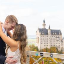 a bride and groom kissing in front of a castle