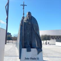 una estàtua d'un home amb una creu davant d'un edifici