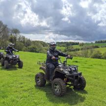 two people riding atvs on a field with