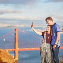 a man and woman taking a picture of the golden gate bridge