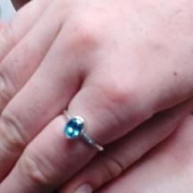a hand holding a ring with a blue sapphire