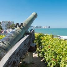 a cannon on a bench next to the ocean