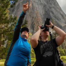 two people are taking pictures of a mountain