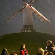 een groep mensen die voor een windmolen staat