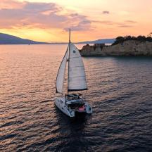 a small sail boat in the water at sunset