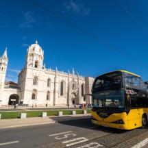 a yellow double decker bus driving past a building
