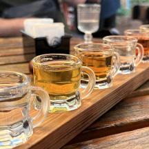 a row of glasses of beer on a wooden table