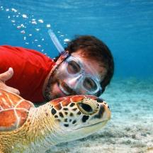 un home amb ulleres i una tortuga a l'aigua