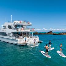 a group of people on surfboards in the water next to a boat