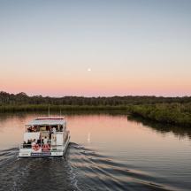 a white boat on a river at sunset