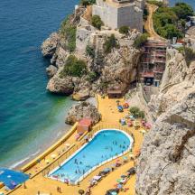 a group of swimming pools on a cliff next to the ocean