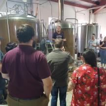 a group of people standing around in a brewery