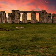an old stone monument on a field with a sunset