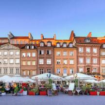a group of buildings with tables and white umbrellas