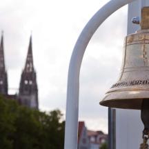 una campana su un edificio con una cattedrale sullo sfondo