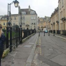 a woman standing next to a fence on a street