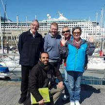 en gruppe mennesker poserer til et billede ved en marina