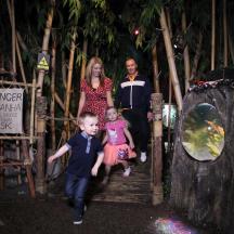 a group of people walking through a wooden gate with two children