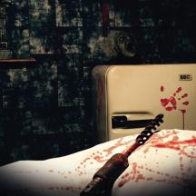 a bottle of wine sitting on a bed with blood