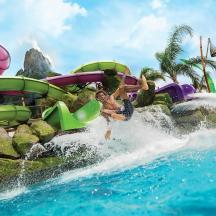 two people jumping off a water slide at a water park