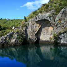 a large rock formation with a face in the water
