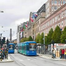 two blue buses on a busy city street with people