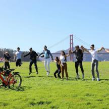 a group of people running in a field with the golden gate bridge