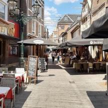 eine leere Straße mit Tischen, Stühlen und Sonnenschirmen