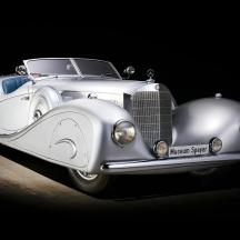 Un viejo coche blanco está aparcado en una habitación oscura.