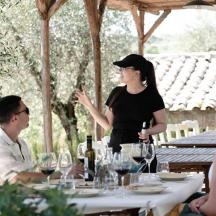 a woman standing at a table talking to a group of people