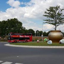 a red double decker bus driving down a road with balls