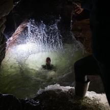 a person in a pool of water in a cave